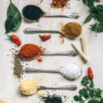 five gray spoons filled with assorted-color powders near chilli