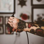 shallow focus photography of person holding black tattoo machine