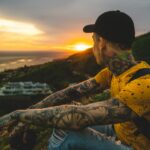 man sitting on hill near cruise ship